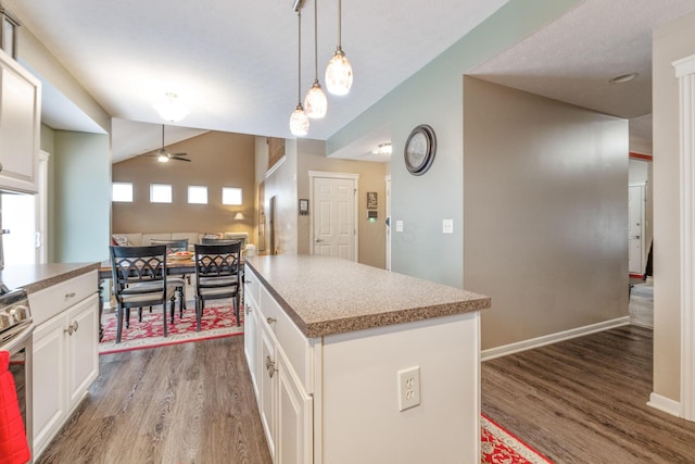 kitchen featuring a center island, pendant lighting, open floor plan, white cabinets, and wood finished floors