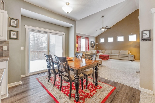 dining space with dark wood-style flooring, vaulted ceiling, and baseboards