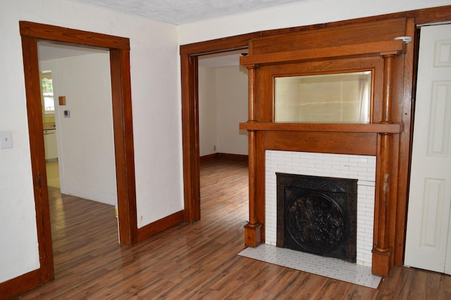 unfurnished living room with a fireplace, a textured ceiling, and dark wood-type flooring