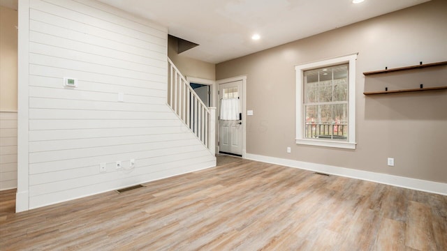 foyer entrance featuring wood walls and light hardwood / wood-style floors