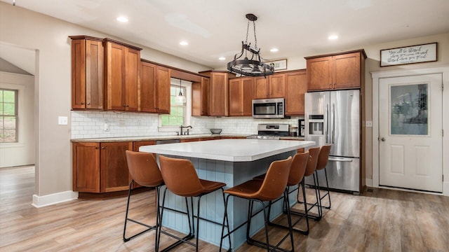 kitchen with pendant lighting, stainless steel appliances, a kitchen island, and a healthy amount of sunlight