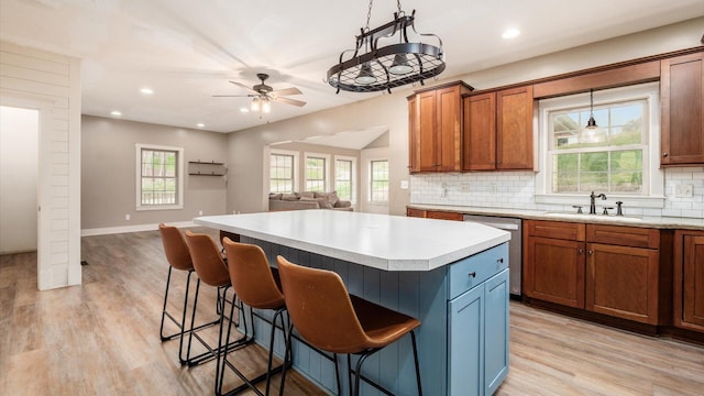 kitchen featuring pendant lighting, plenty of natural light, a kitchen island, and stainless steel dishwasher