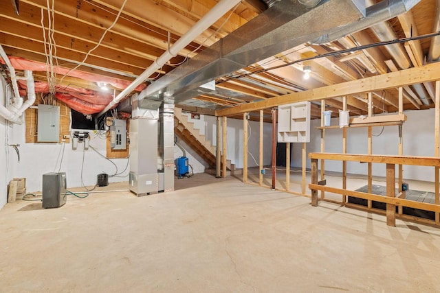 basement featuring electric panel and heating unit