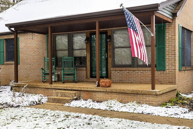 snow covered property entrance with a porch