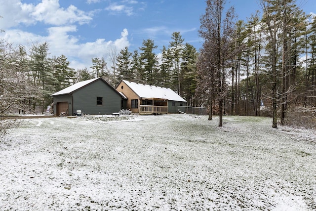 snow covered house featuring an outdoor structure and a garage