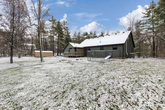 yard layered in snow featuring a storage shed, cooling unit, and a deck