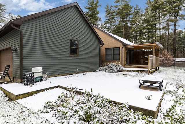 snow covered rear of property with a garage