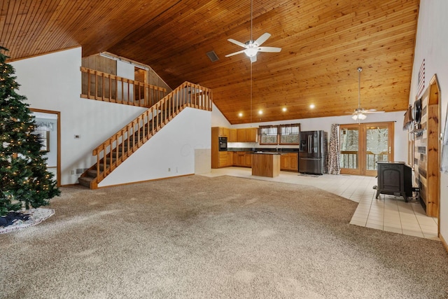 unfurnished living room with a wood stove, high vaulted ceiling, ceiling fan, and wood ceiling