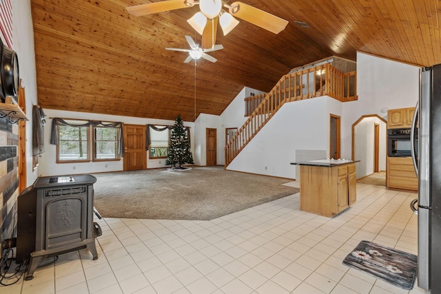 interior space with light carpet, wood ceiling, a wood stove, high vaulted ceiling, and oven