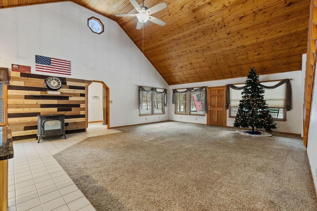 unfurnished living room with ceiling fan, light tile patterned floors, high vaulted ceiling, wooden ceiling, and a wood stove