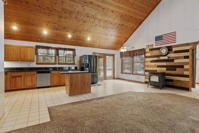 kitchen with a wood stove, high vaulted ceiling, plenty of natural light, and stainless steel dishwasher