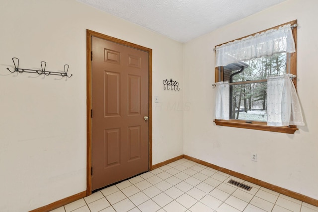 entryway with light tile patterned floors and a textured ceiling