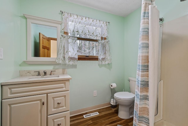 bathroom with curtained shower, a textured ceiling, toilet, vanity, and hardwood / wood-style flooring