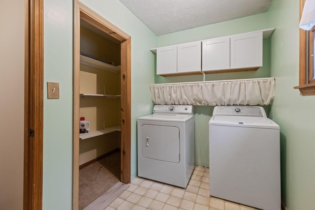 laundry room with washer and clothes dryer, cabinets, and a textured ceiling