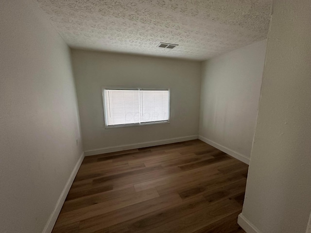 unfurnished room with dark wood-type flooring and a textured ceiling