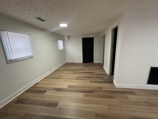 corridor with light wood-type flooring and a textured ceiling