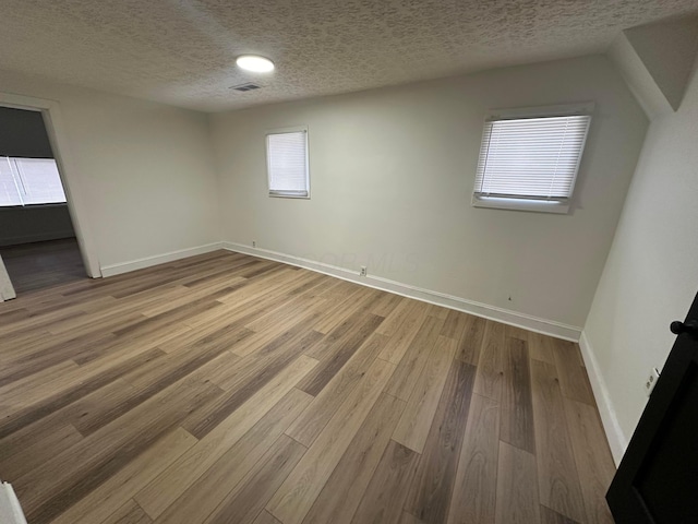 empty room with wood-type flooring and a textured ceiling