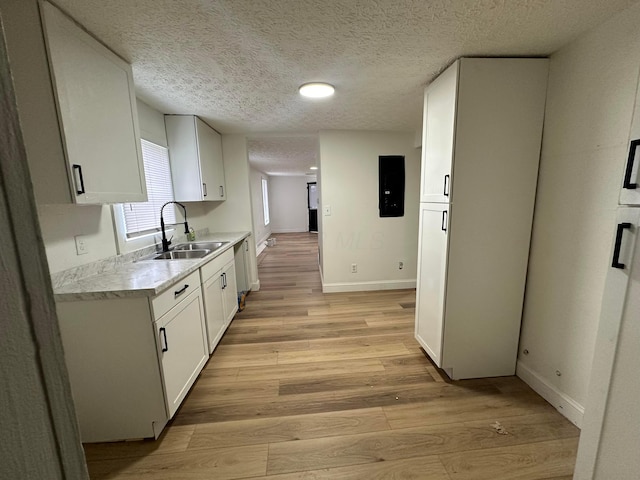 kitchen with white cabinetry, sink, a textured ceiling, and light wood-type flooring