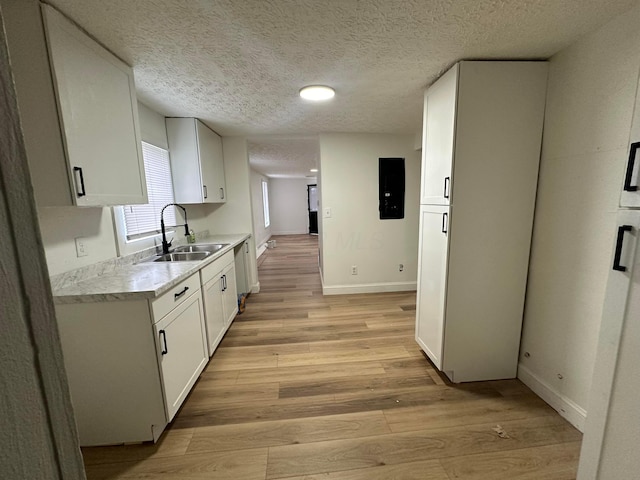 kitchen with white cabinets, light wood-type flooring, stainless steel dishwasher, and sink