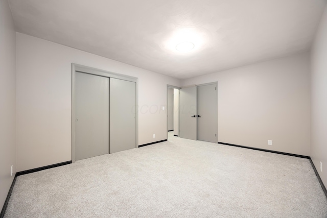 unfurnished bedroom featuring a closet and light colored carpet