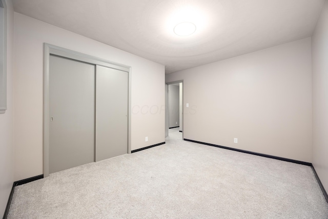 unfurnished bedroom featuring a closet and light colored carpet