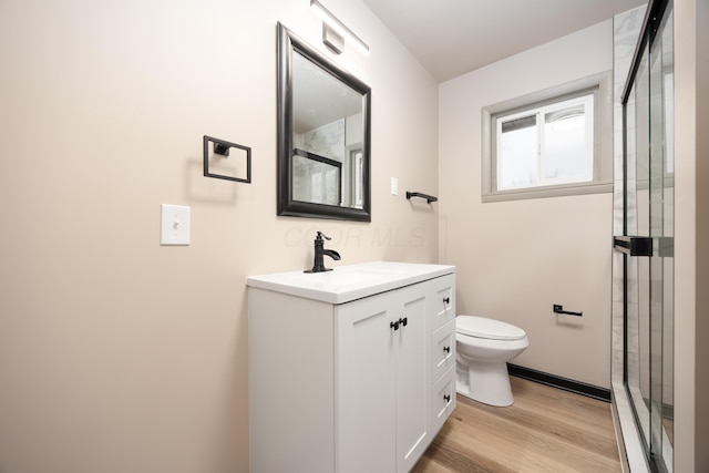 bathroom with walk in shower, vanity, wood-type flooring, and toilet