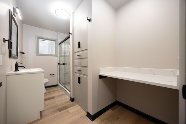 bathroom with vanity, toilet, wood-type flooring, and a shower with door