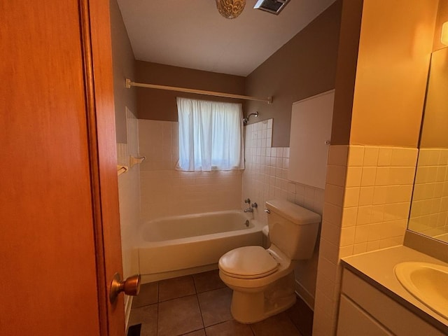 full bathroom with vanity, tile patterned flooring, tiled shower / bath combo, toilet, and tile walls