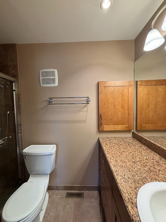 bathroom with tile patterned floors, vanity, toilet, and a shower with door