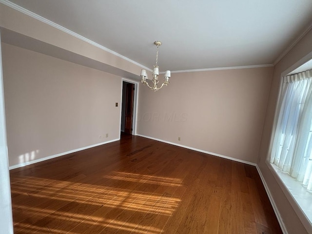 spare room with a healthy amount of sunlight, dark hardwood / wood-style flooring, crown molding, and an inviting chandelier