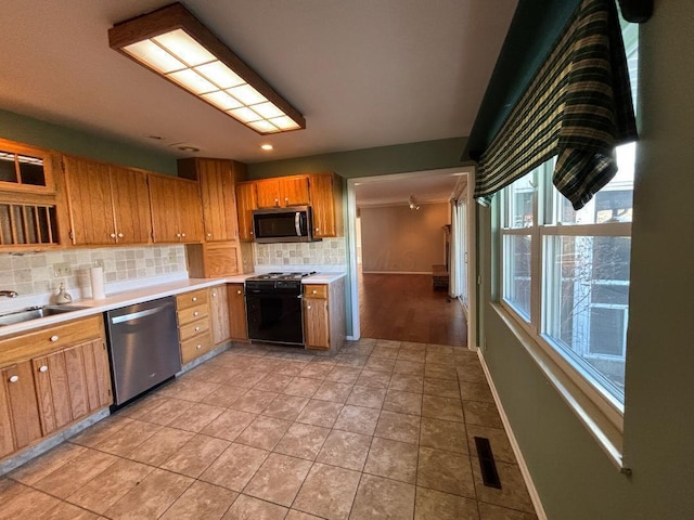 kitchen featuring sink, backsplash, crown molding, light tile patterned floors, and appliances with stainless steel finishes