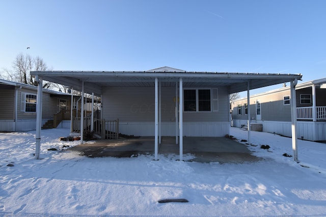 snow covered house featuring a carport