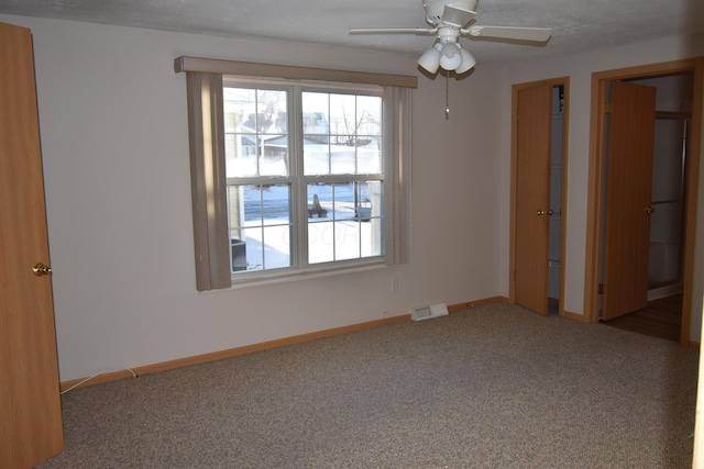 spare room with a textured ceiling, ceiling fan, and carpet flooring