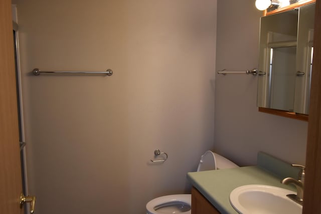 bathroom featuring toilet, a shower with door, and vanity