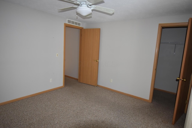 unfurnished bedroom featuring ceiling fan, a closet, a spacious closet, and carpet floors