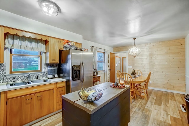 kitchen with pendant lighting, an inviting chandelier, sink, light hardwood / wood-style flooring, and stainless steel fridge