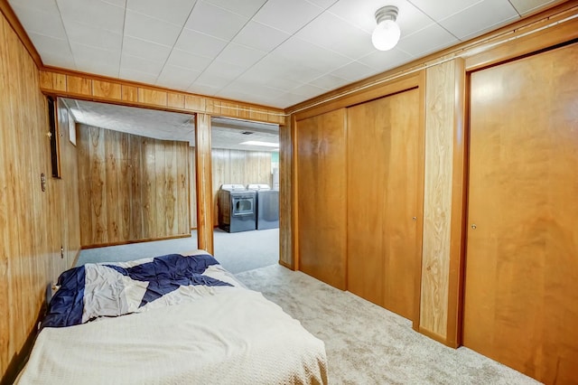 bedroom with carpet flooring, wooden walls, and washer and dryer