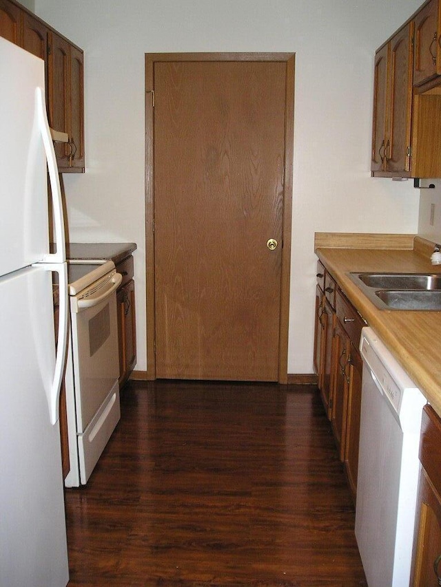 kitchen with dark hardwood / wood-style flooring, white appliances, and sink