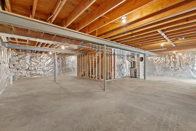 basement featuring electric panel and heating unit