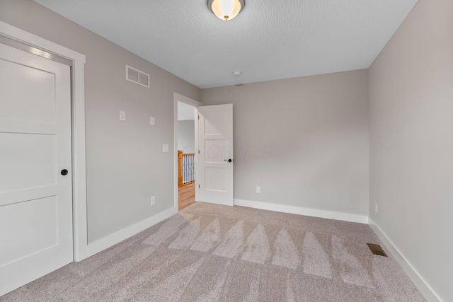 unfurnished bedroom with a textured ceiling and light colored carpet