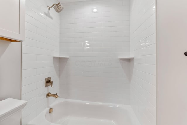 bathroom featuring tiled shower / bath combo and toilet