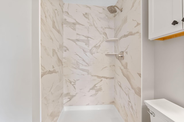 bathroom featuring a tile shower and toilet