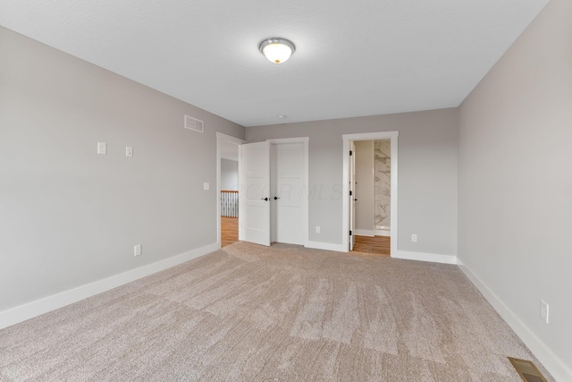 unfurnished bedroom with ensuite bath, light carpet, and a closet