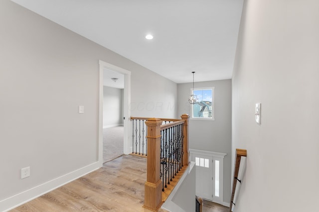 hallway featuring an inviting chandelier and light hardwood / wood-style flooring