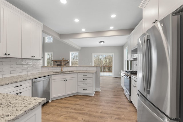 kitchen featuring white cabinetry, sink, stainless steel appliances, light stone counters, and light wood-type flooring