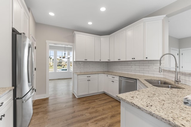 kitchen featuring decorative backsplash, appliances with stainless steel finishes, sink, white cabinets, and hardwood / wood-style floors