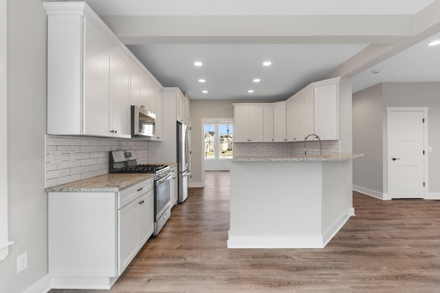 kitchen with white cabinets, hardwood / wood-style flooring, and appliances with stainless steel finishes