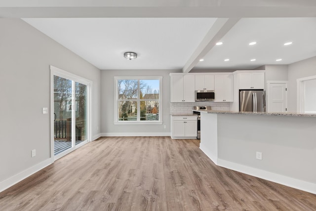 kitchen with backsplash, white cabinets, light hardwood / wood-style flooring, light stone countertops, and appliances with stainless steel finishes