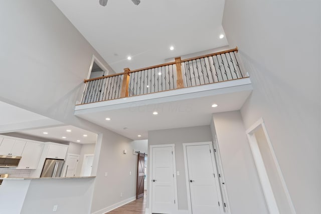 interior space with a towering ceiling, light wood-type flooring, and a barn door