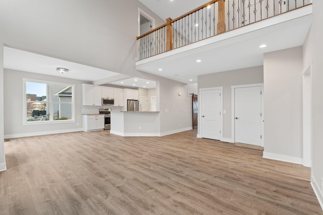 unfurnished living room with a high ceiling and light hardwood / wood-style flooring